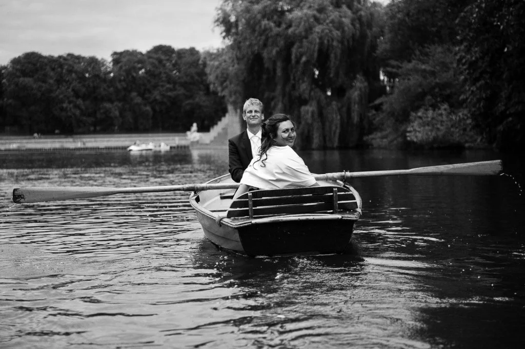 Freudiges Hochzeitspaar im romantischen Ruderboot auf dem Stadtparksee in Hamburg Winterhude bei den Brautpaarfotos beim Hochzeitsfotograf Hamburg