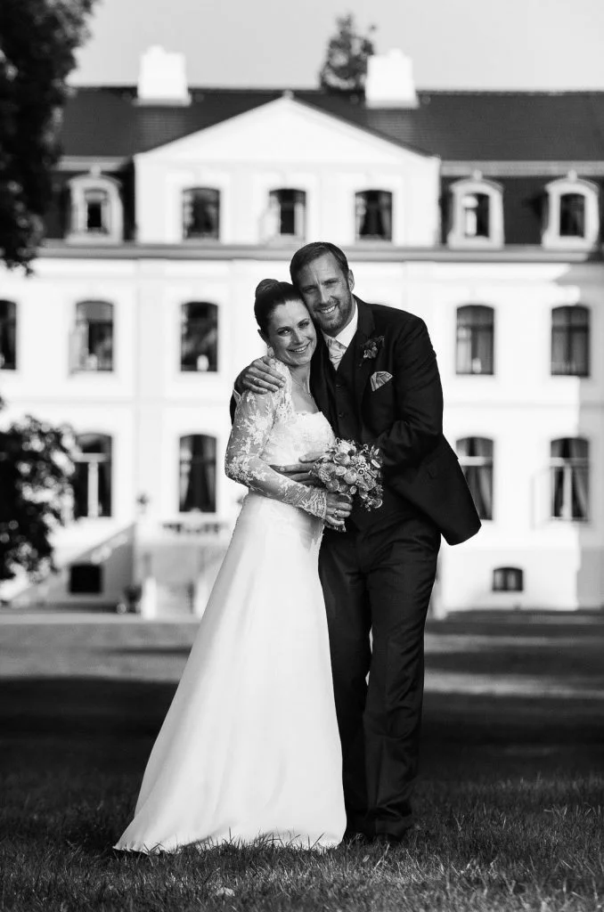 bRaut und Bräutigam posieren vor dem Schloß Weissenhaus Grand Village Resort am Weissenhäuser Strand an der Ostsee beim Hochzeitsfotograf Hamburg