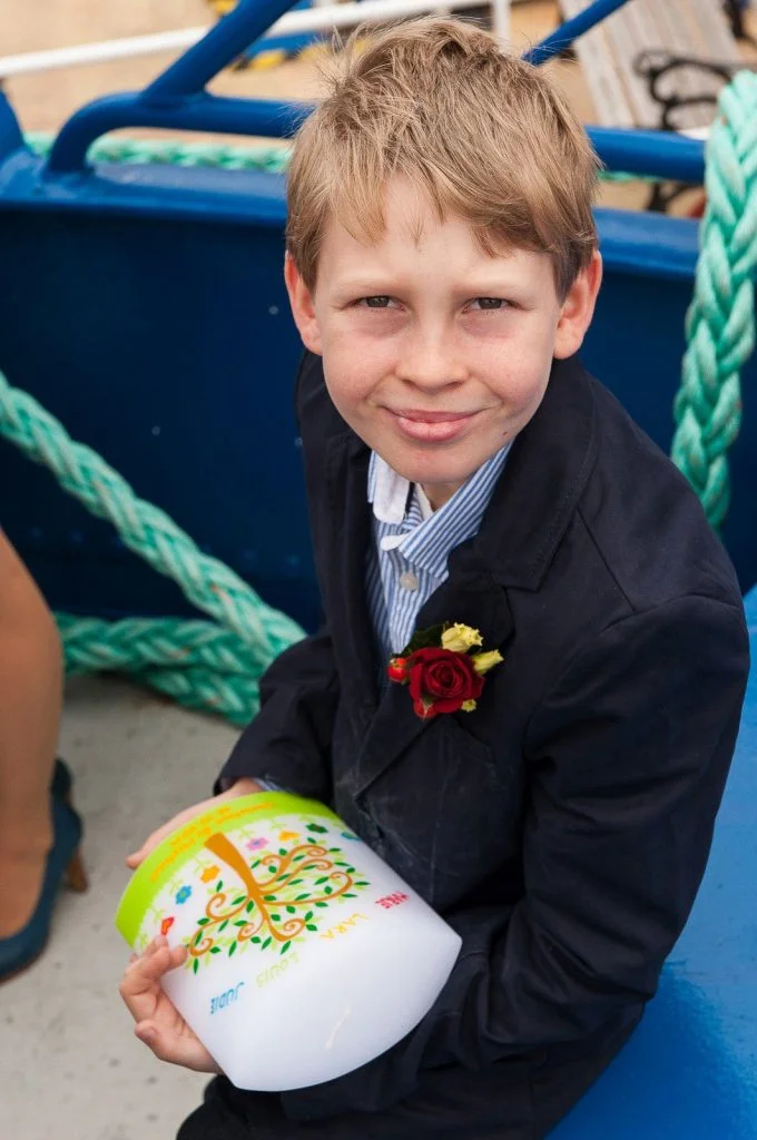 Der Sohn des Bräutigams hält die Taufkerze auf der Flußschifferkirche. Die Hochzeitsbilder vom Hochzeitsfotograf Hamburg