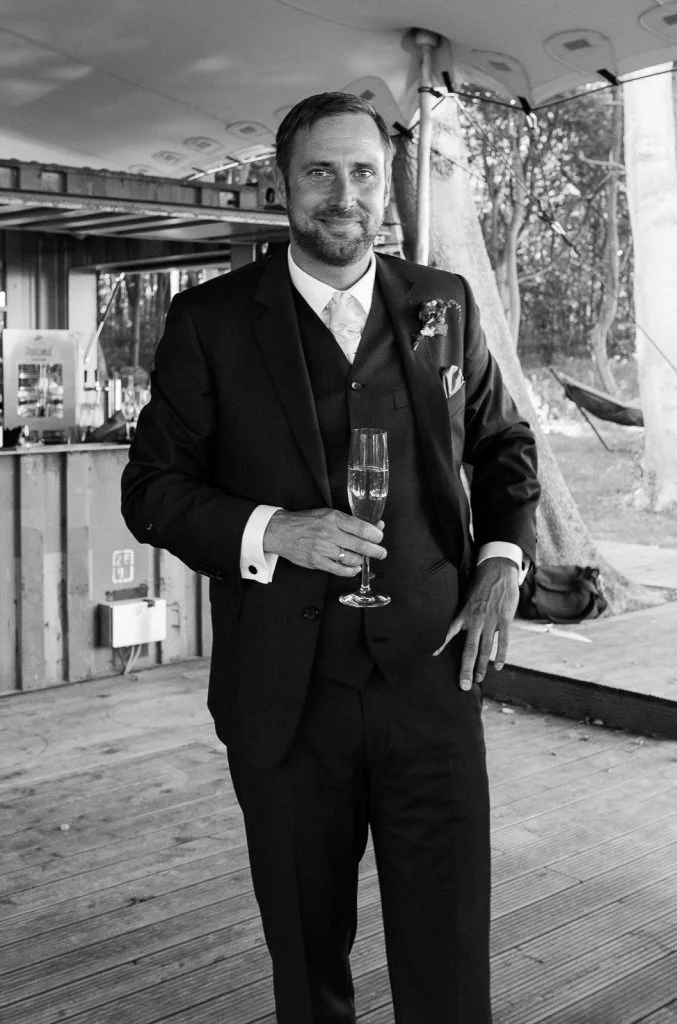 Glückseeliger Bräutigam beim Sektempfang im Bootshaus vom Schloß Weissenhaus Grand Village Resort am Weissenhäuser Strand an der Ostsee beim Hochzeitsfotograf Hamburg