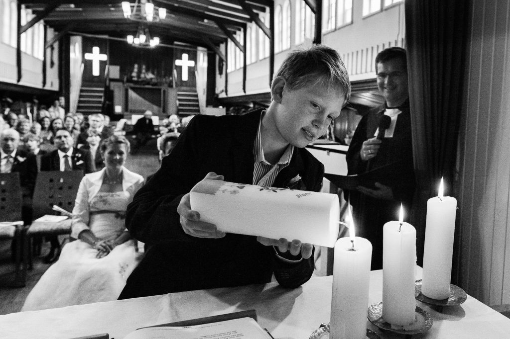 Der Sohn zündet die Taufkerze am Altar in der Flußschifferkirche an. Die Hochzeitsbilder vom Hochzeitsfotograf Hamburg