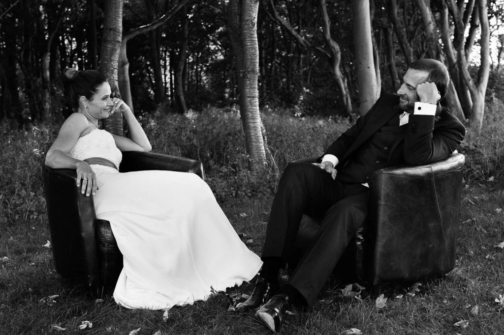 Hochzeitspaar flirtet in Vintage Ledersesseln im Küstenwald am Weissenhäuser Strand an der Ostsee beim Hochzeitsfotograf Hamburg