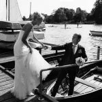 Der Bräutigam hilft seiner Braut in ein Ruderboot am Bobby Reich Bootsteg an der Außenalster in Harvestehude beim Hochzeitsfotograf Hamburg