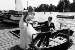 Der Bräutigam hilft seiner Braut in ein Ruderboot am Bobby Reich Bootsteg an der Außenalster in Harvestehude beim Hochzeitsfotograf Hamburg