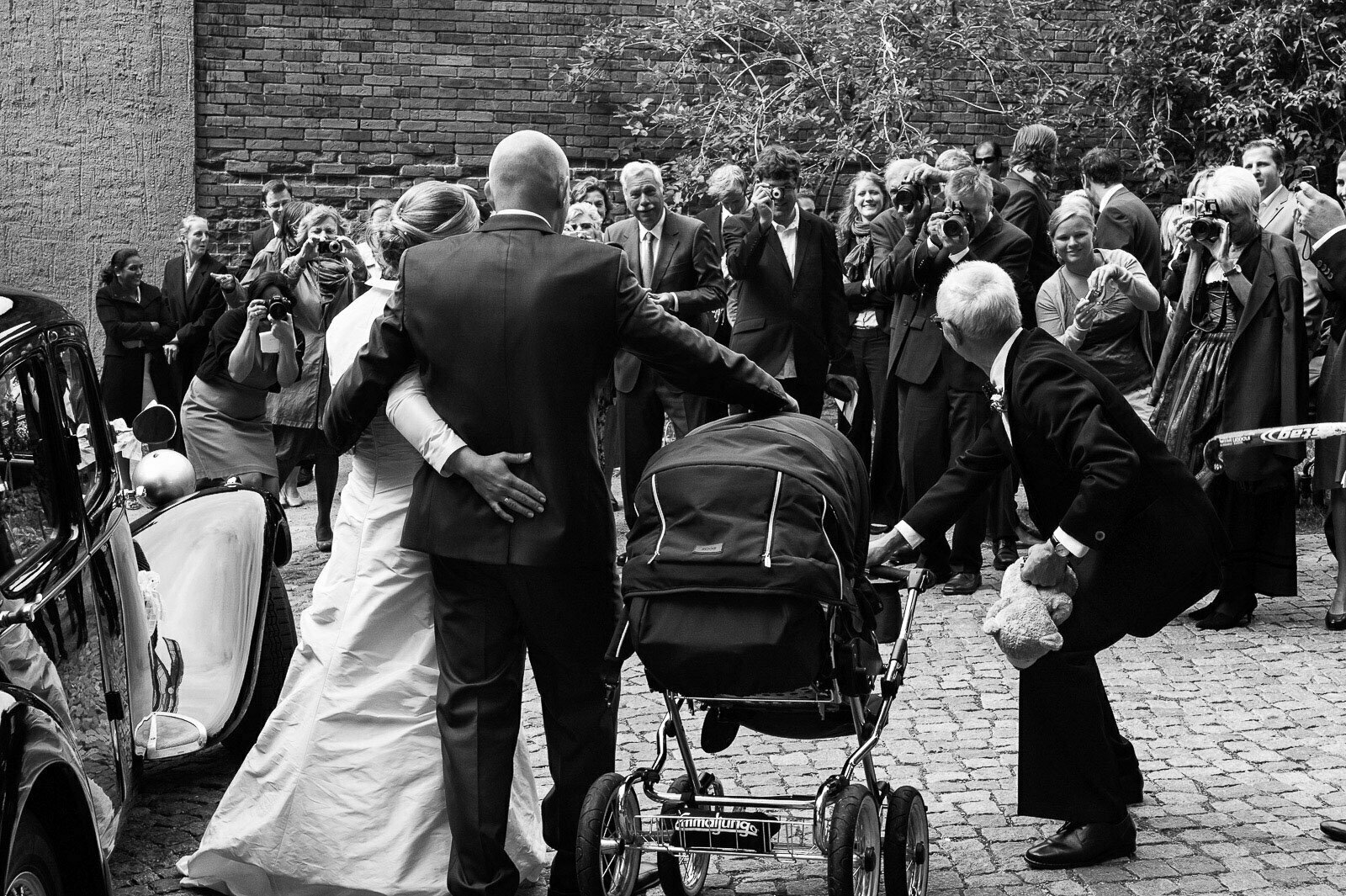 Hochzeitspaar posiert vor seinen Hochzeitsgästen nach der Trauung für das Hochzeitsfoto vor der Sankt Marien Kirche in Röbel an der Müritz in Mecklenburg Vorpommern beim Hochzeitsfotograf Landhochzeit Hamburg