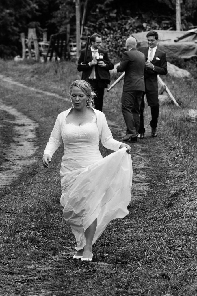 Hochzeitspaar mit Hochzeitsgästen bei der Landhochzeit läuft gemeinsam über die Felder am Gutshof Woldzegarten in Mecklenburg Vorpommern beim Hochzeitsfotograf Landhochzeit Hamburg
