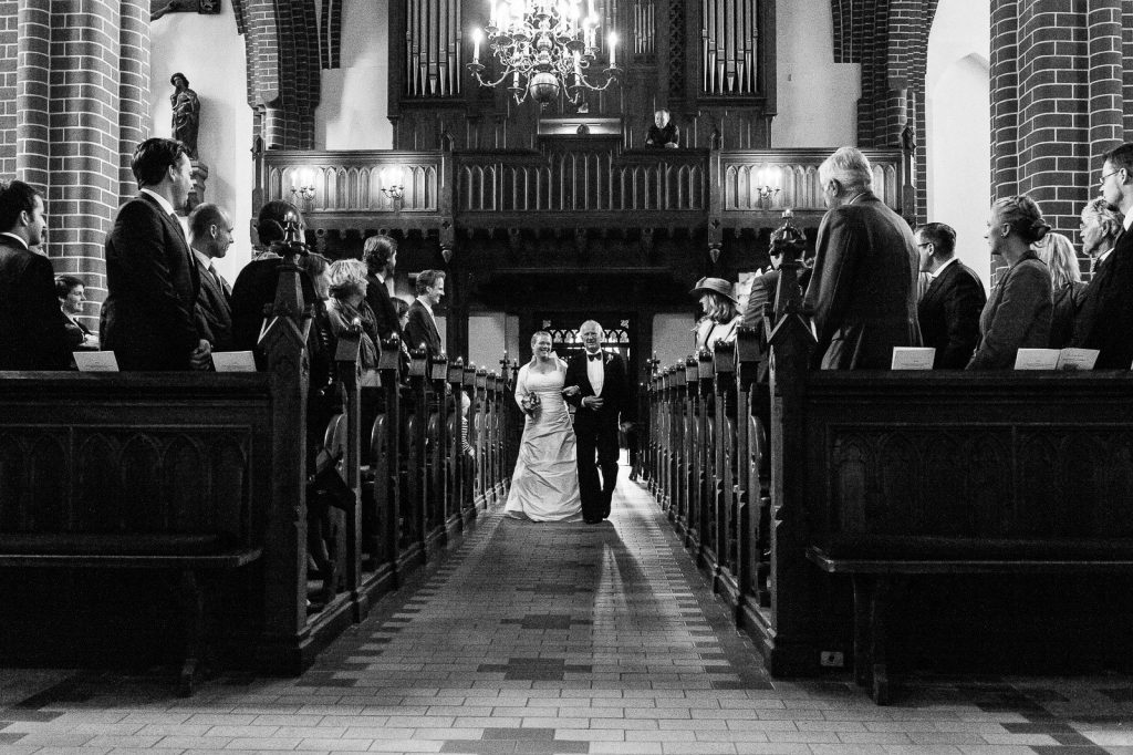Brautvater führt die Braut beim Einzug in die Sankt Marien Kirche in Röbel an der Müritz in Mecklenburg Vorpommern beim Hochzeitsfotograf Landhochzeit Hamburg