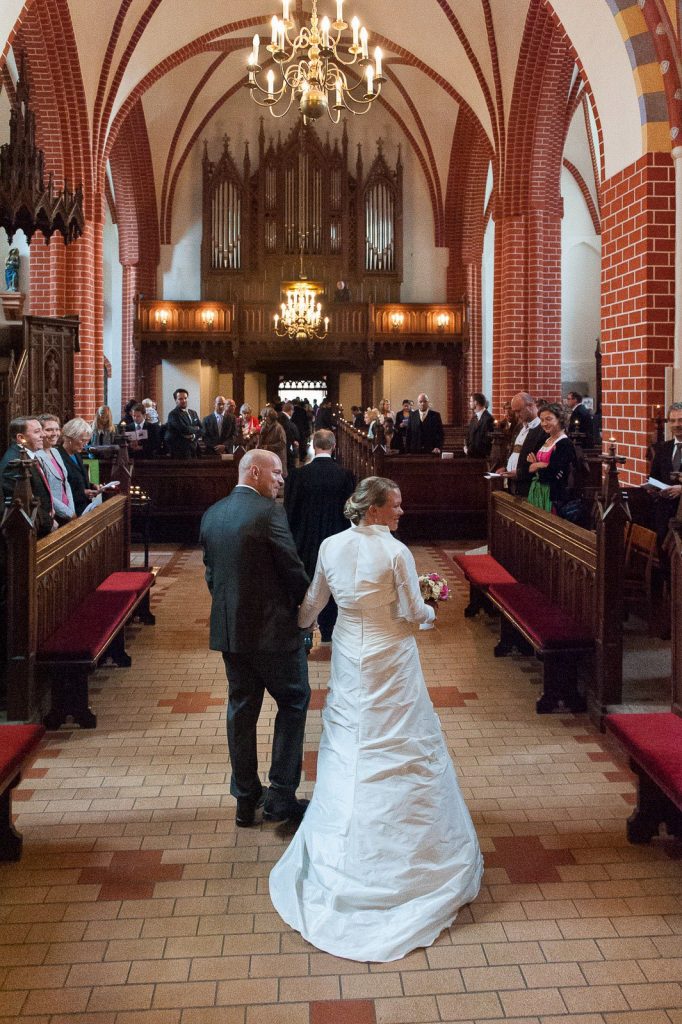 Hochzeitspaar Hand in Hand beim Auszug aus der Sankt Marien Kirche in Röbel an der Müritz in Mecklenburg Vorpommern beim Hochzeitsfotograf Landhochzeit Hamburg