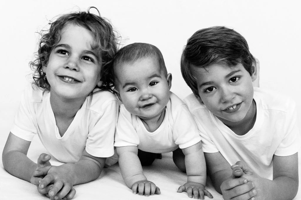 Zwei Jungs liegen gemeinsam mit ihrer kleinen Schwester auf dem Bauch bei der Kinderfotografie in Hamburg Eimsbüttel
