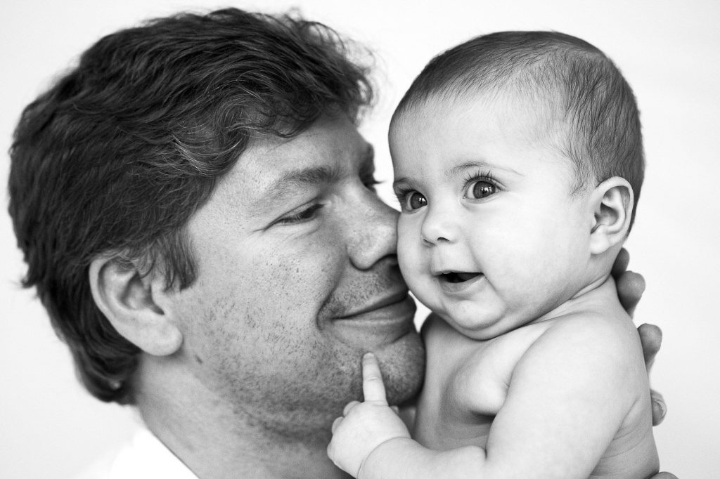 Papa kuschelt mit seinem Baby beim Baby Fotoshooting bei natuerlichem Licht