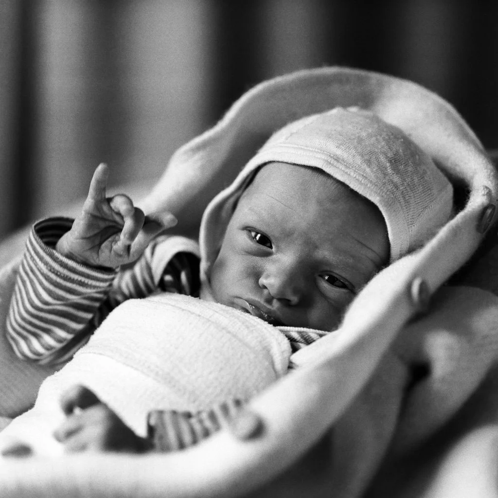 Baby mit Mützchen hebt den kleinen Finger beim Baby Shooting in Hamburg Altona