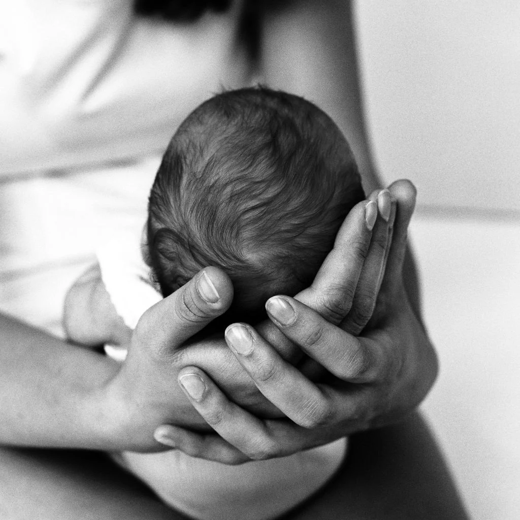 Mama hält den Babykopf mit beiden Händen beim Baby Shooting in Hamburg Rotherbaum