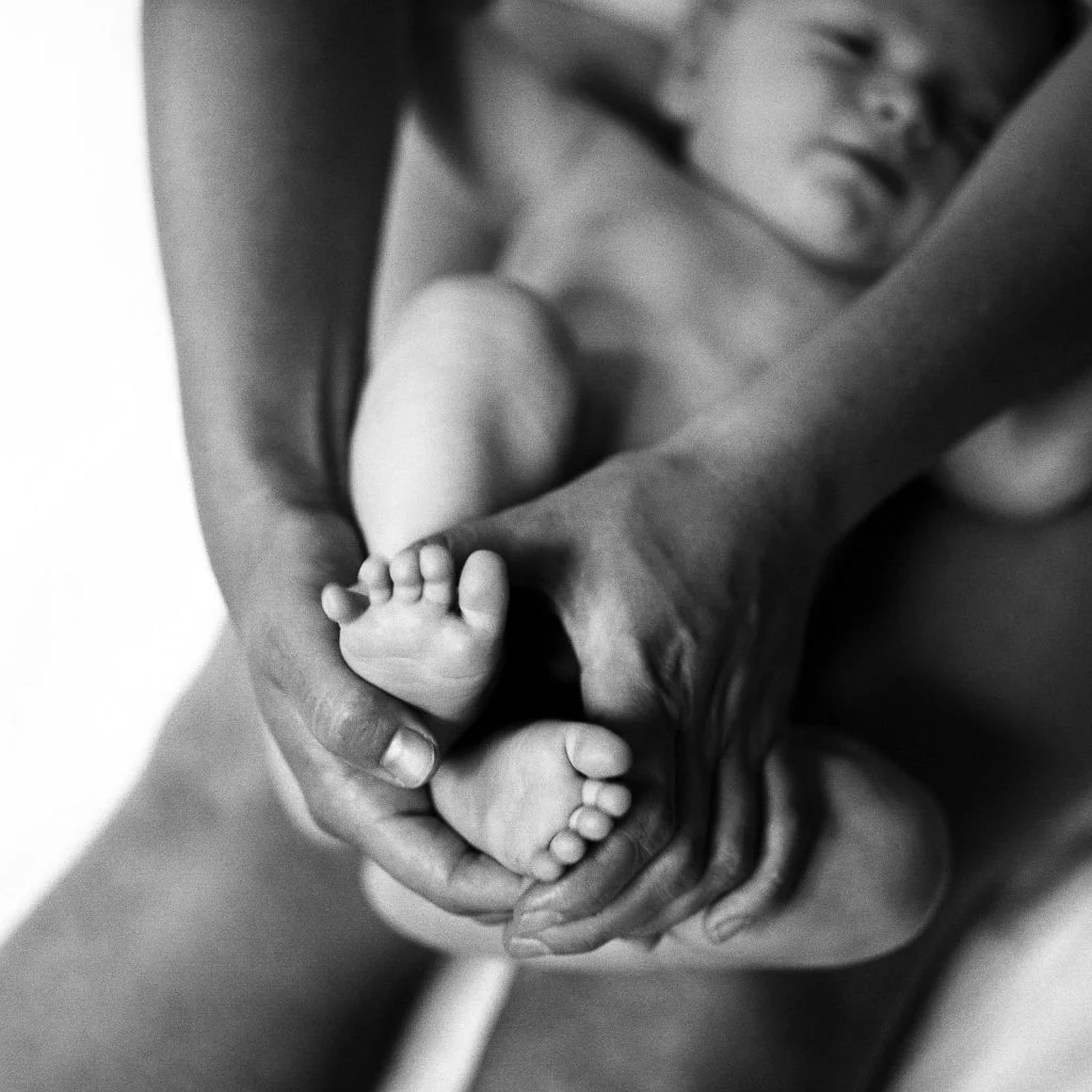 Baby Fotoshooting zuhause mit dem Tageslicht, Babyfuesse in den Haenden der Mutter