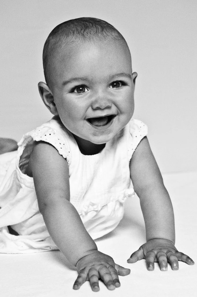 Lachendes Baby auf die Arme gestützt beim Baby Fotoshooting zuhause