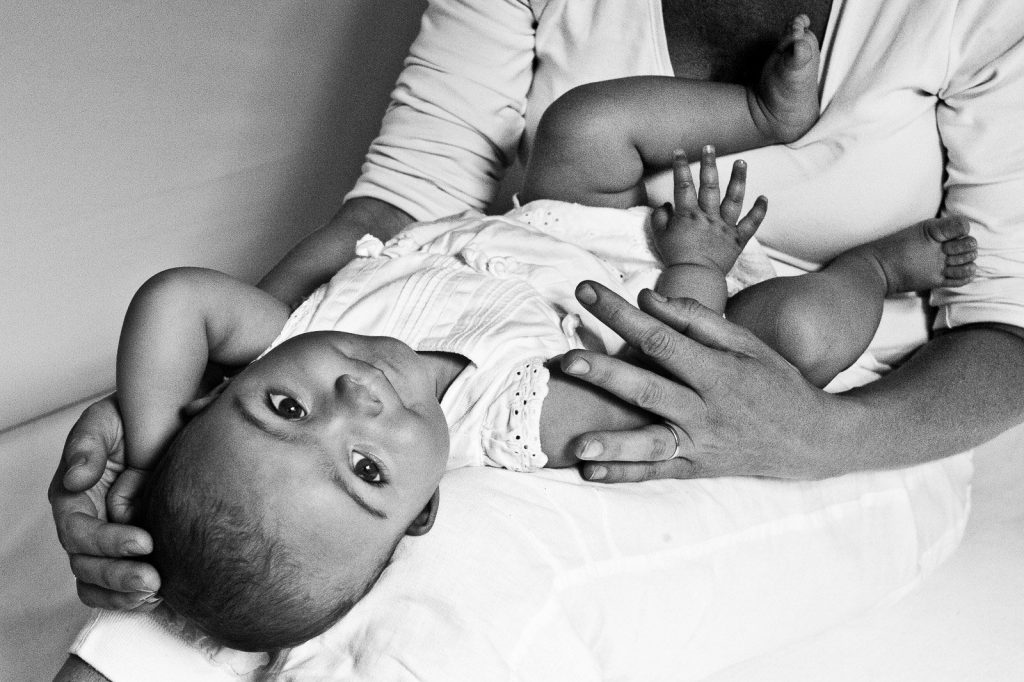 Baby liegt auf den Beinen der Mama und wird gestreichelt beim Baby Fotoshooting in Hamburg-Altona