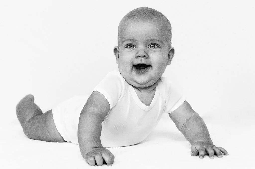 Baby liegt auf dem Bauch und stützt sich auf die Arme beim Baby Fotoshooting in Hamburg Eppendorf