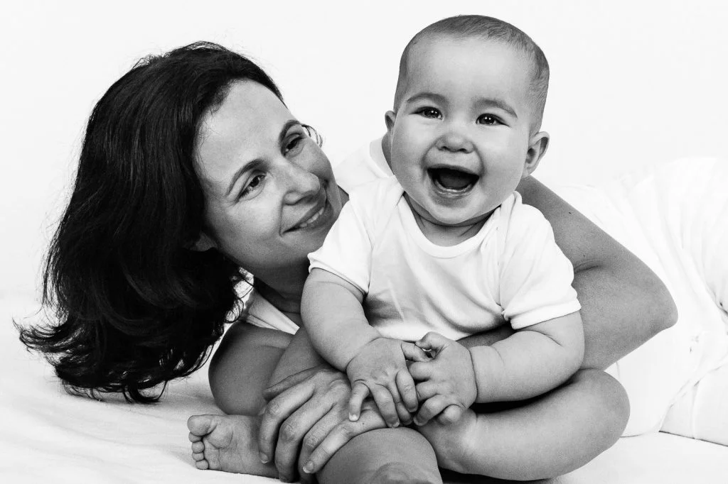 Mama hält sitzendes Baby fest und lacht es an beim Baby Fotoshooting in Hamburg Eimsbüttel