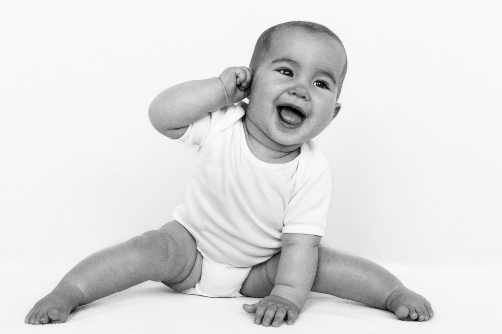 Baby sitzt auf dem Boden und zieht an seinem Ohr beim Baby Fotoshooting in Hamburg Eimsbüttel
