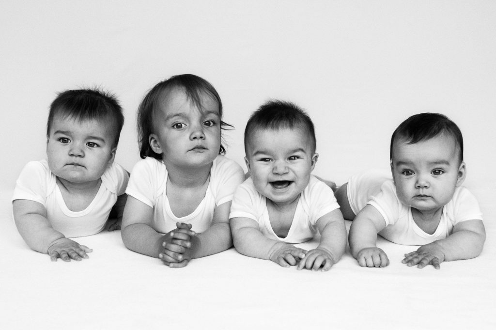 Drillinge mit großer Schwester gemeinsam auf dem Bauch liegend beim Baby Fotoshooting in Hamburg Eimsbüttel