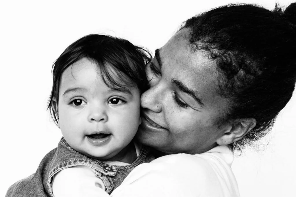Baby und Mama kuscheln Wange an Wange beim Baby Fotoshooting zuhause in Hamburg Eppendorf