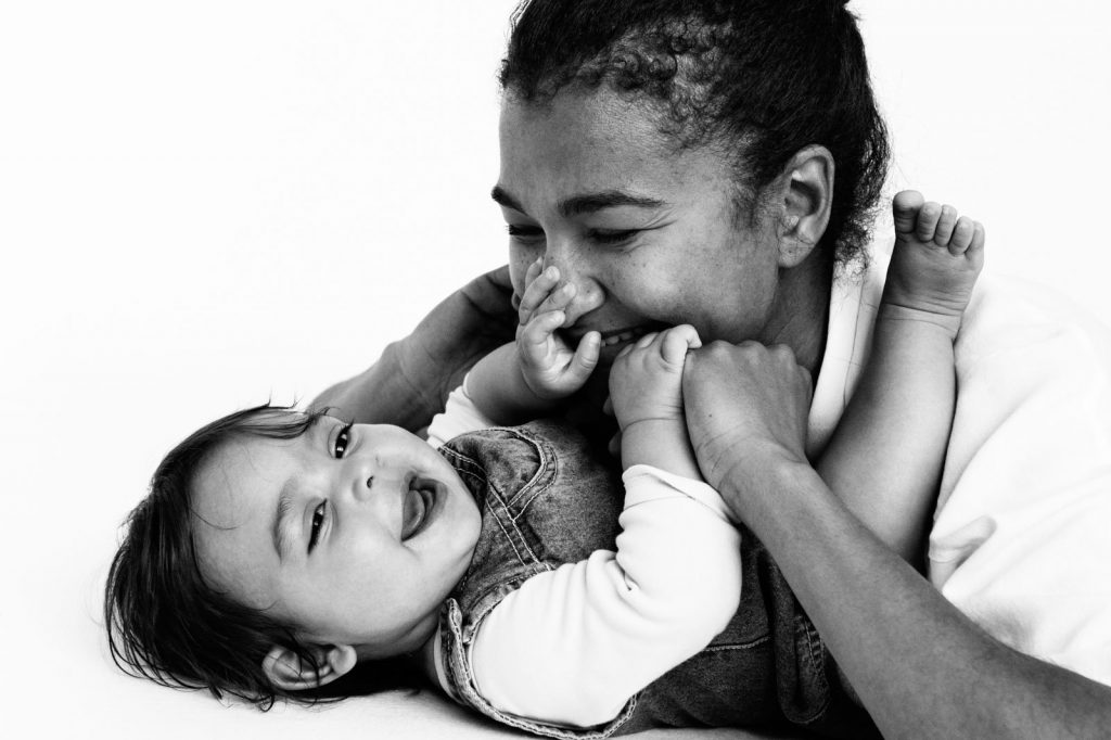 Baby greift an Mamas Nase beim Baby Fotoshooting zuhause in Hamburg Eppendorf