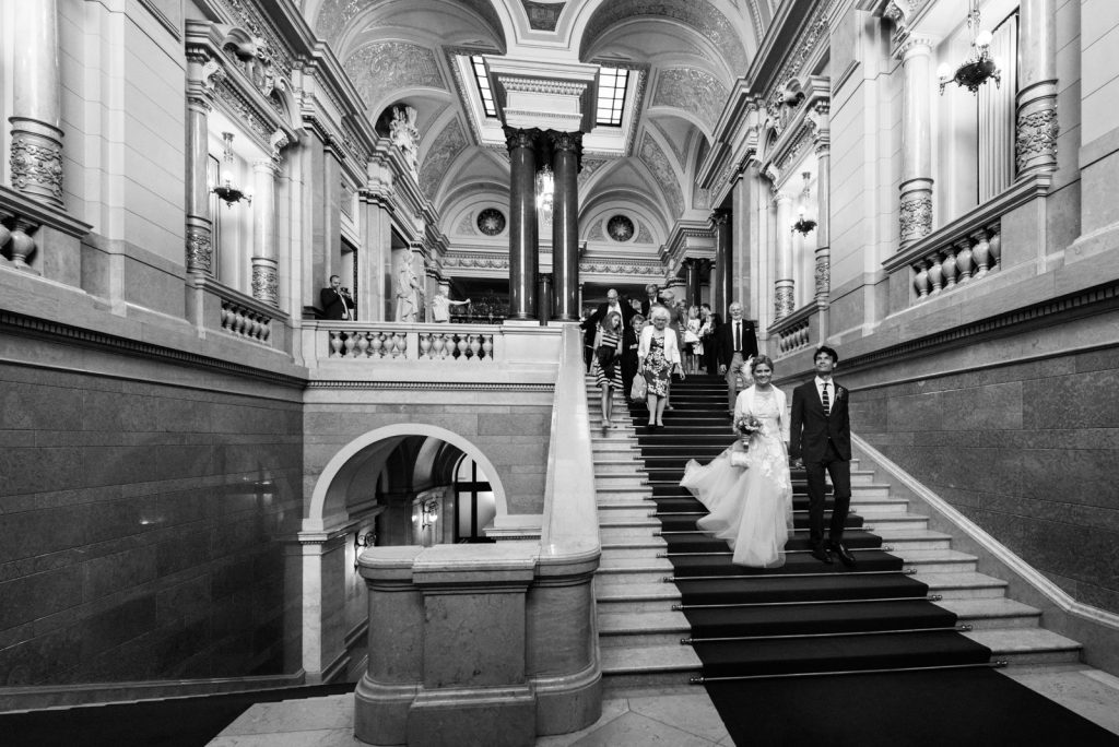 Das frisch vermählte Brautpaar verläßt nach der Trauung im Phönixsaal über die weitläufigen Treppen das Hamburger Rathaus beim Hochzeitsfotograf Hamburg