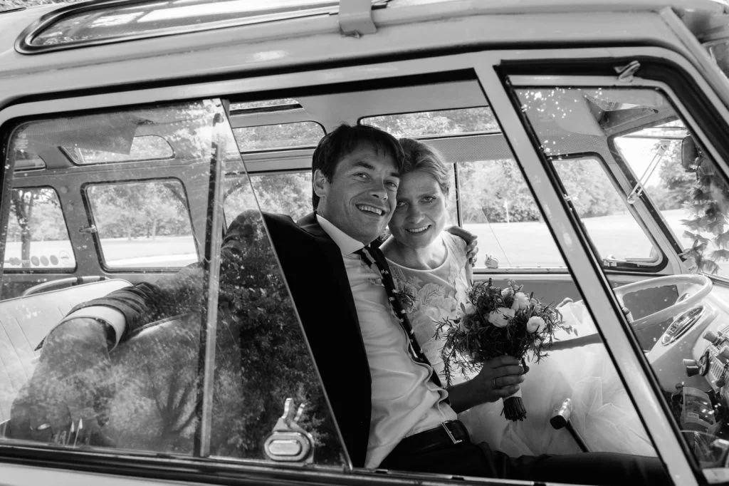 Braut und Bräutigam genießen eine Fahrt mit dem Hochzeitsauto VW Bus T1 am Goldschätzchen der Koch Fabrik auf dem Golf Park Peiner Hof in Priesdorf beim Hochzeitsfotograf Hamburg