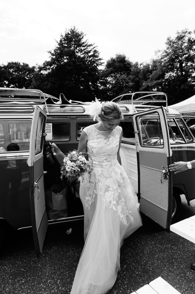 Die Braut steigt aus dem Hochzeitsauto VW Bus T1 am Goldschätzchen der Koch Fabrik auf dem Golf Park Peiner Hof in Priesdorf beim Hochzeitsfotograf Hamburg