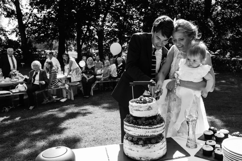 Das Hochzeitspaar schneidet gemeinsam die Hochzeitstorte an am Goldschätzchen der Koch Fabrik auf dem Golf Park Peiner Hof in Priesdorf beim Hochzeitsfotograf Hamburg