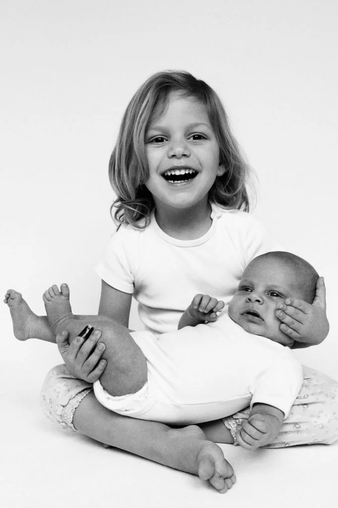 Baby und große kleine Schwester turnen gemeinsam auf der Tagesdecke beim Baby Fotoshooting zuhause in Hamburg Poppenbüttel