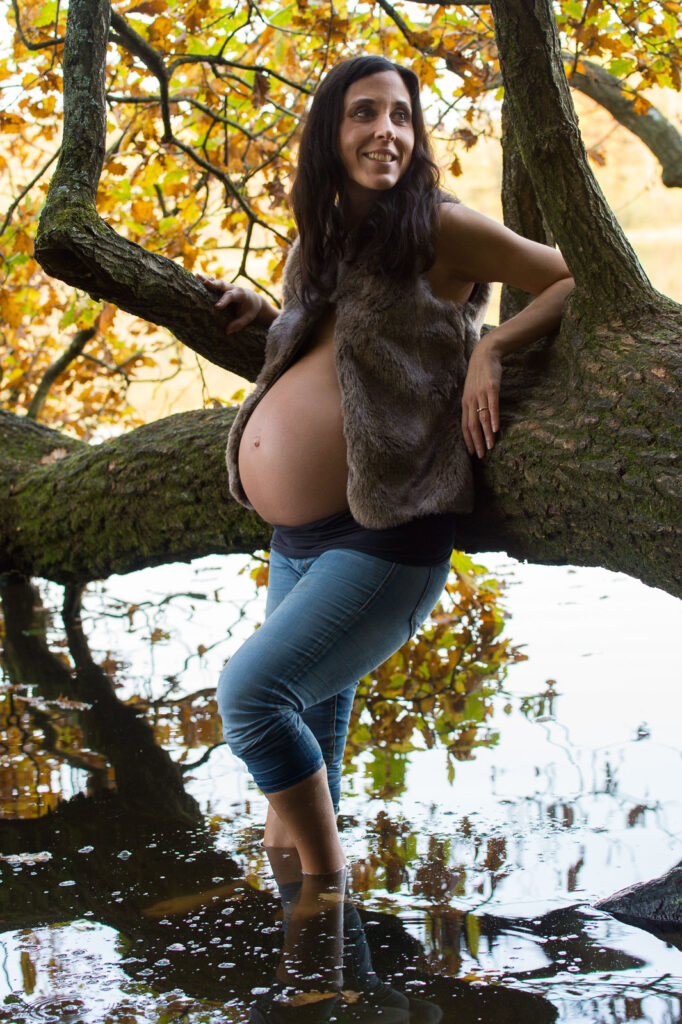 Schwangere im Wasser am Baum mit Herbstlaub bei den Babybauchfotos in Hamburg am See in der Natur
