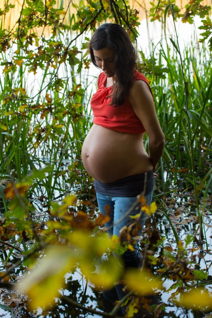 Schwangere steht im Schilf am Seeufer bei den Babybauchfotos in Hamburg draußen in der Natur