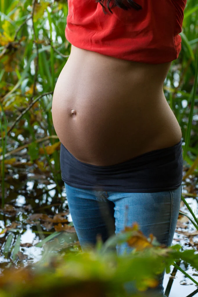 Schwangere steht im Schilf am Seeufer bei den Babybauchfotos in Hamburg draußen in der Natur