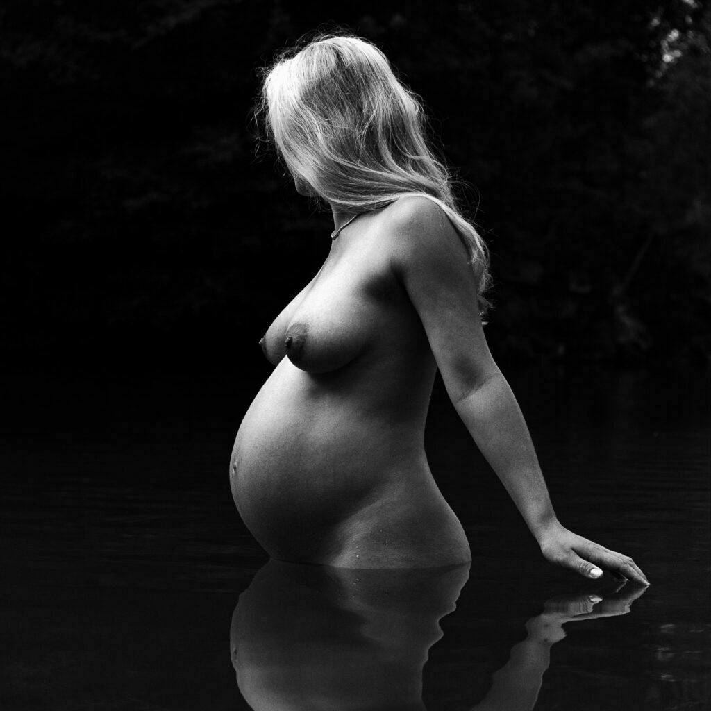 Seitenansicht einer Schwangeren im See stehend bei den Babybauchfotos in Hamburg in der Natur