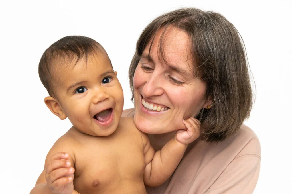 Baby kuschelt mit Mama und blickt beim Baby Fotoshooting zuhause in Hamburg
