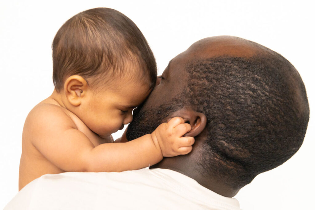 Baby kuschelt mit Papa beim Baby Fotoshooting zuhause in Hamburg