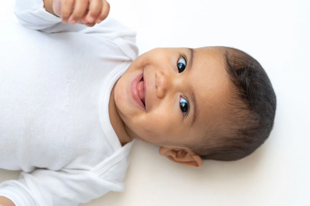 Lachendes Babygesicht beim Baby Fotoshooting mit dem Tageslicht zuhause in Hamburg