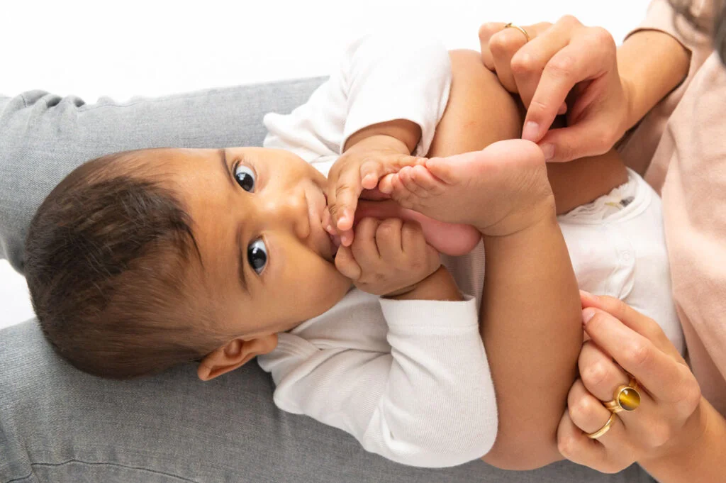 Baby Fotoshooting zuhause mit dem Tageslicht, Babyfuesse in den Haenden der Mutter zuhause in Hamburg